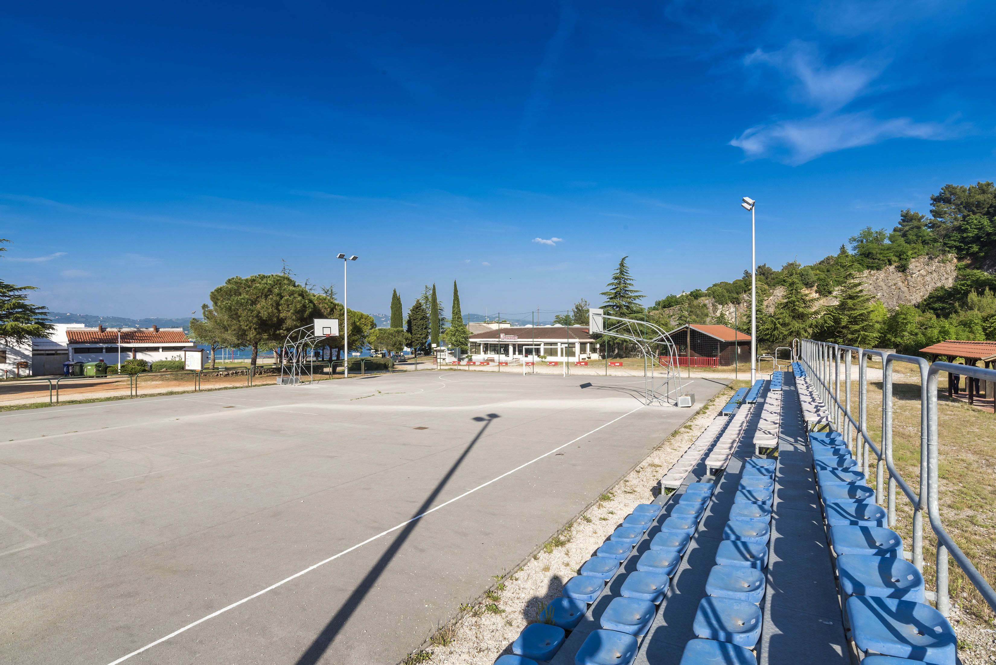 Ein Sportplatz im Freien mit blauen Sitzgelegenheiten und blauem Himmel.
