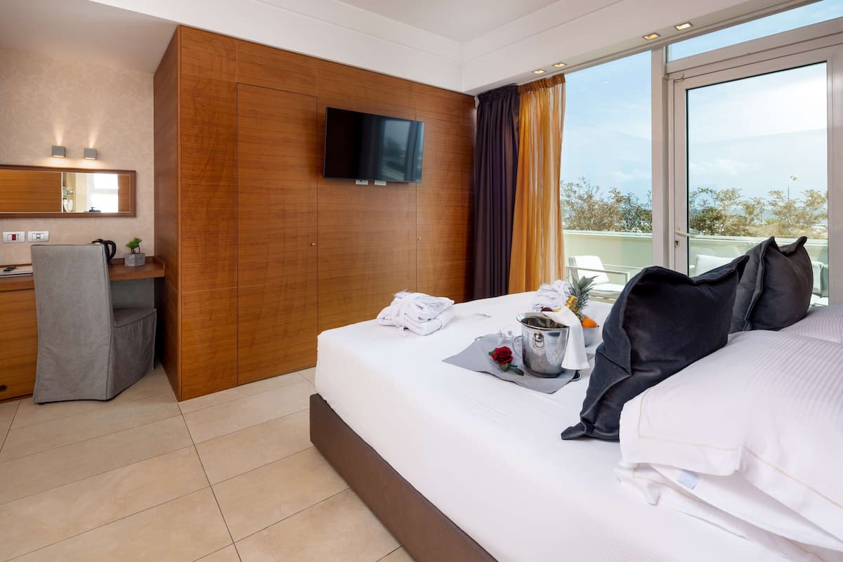 A hotel room with a bed, a desk, a TV, and a large window with curtains.