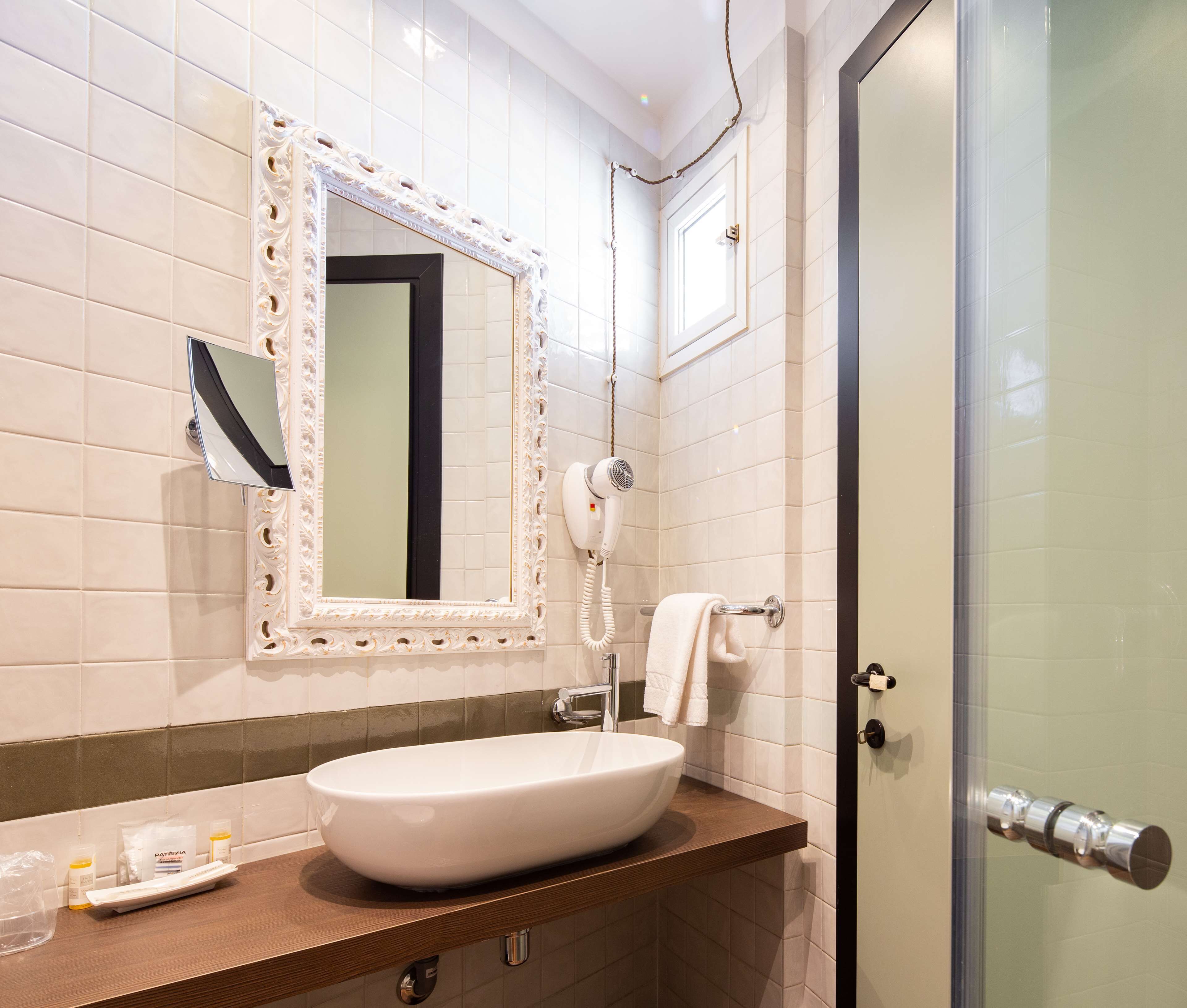 Un baño con un espejo grande, un lavamanos, un secador de pelo y una puerta de ducha de vidrio.