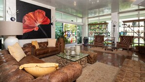 Ein großzügiges Wohnzimmer mit Ledersofas, einem Glastisch und einem großen Fenster mit Blick ins Freie.