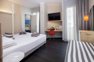 Una camera d'albergo con un letto, una scrivania, una TV e una sedia.
