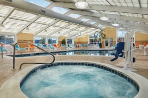 An indoor swimming pool with a clear view of the sky through the roof, surrounded by lounge chairs and a poolside area. - Holiday Inn Gulfport Airport by IHG (Gulfport)