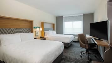A hotel room with two beds, a desk with a computer, a TV, and a window with blinds.