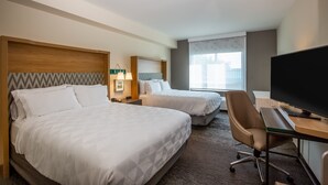 Habitación de hotel con dos camas, un escritorio con televisor y una silla.