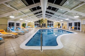 An indoor swimming pool with multiple lanes, surrounded by sun loungers and a high ceiling with skylights. - Holiday Inn Gulfport Airport by IHG (Gulfport)