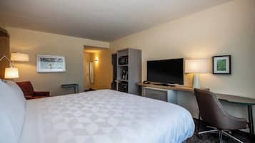 A hotel room with a large bed, a desk with a computer, a TV, and a chair.
