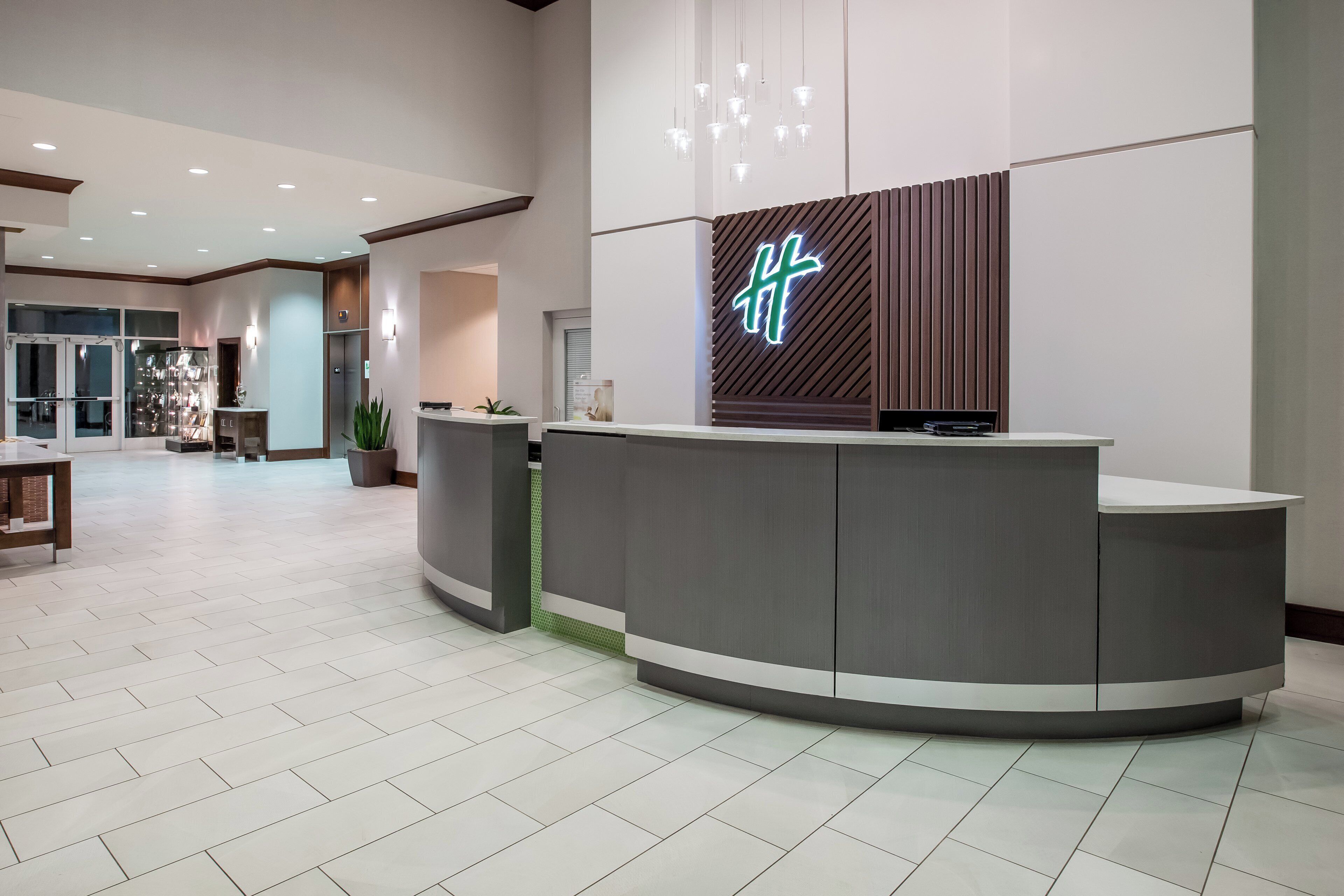 A hotel reception area with a modern design, including a reception desk, a digital display, and a reception counter.
