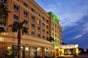 Un hotel de varios pisos con un cartel verde llamativo que indica que es un Holiday Inn.