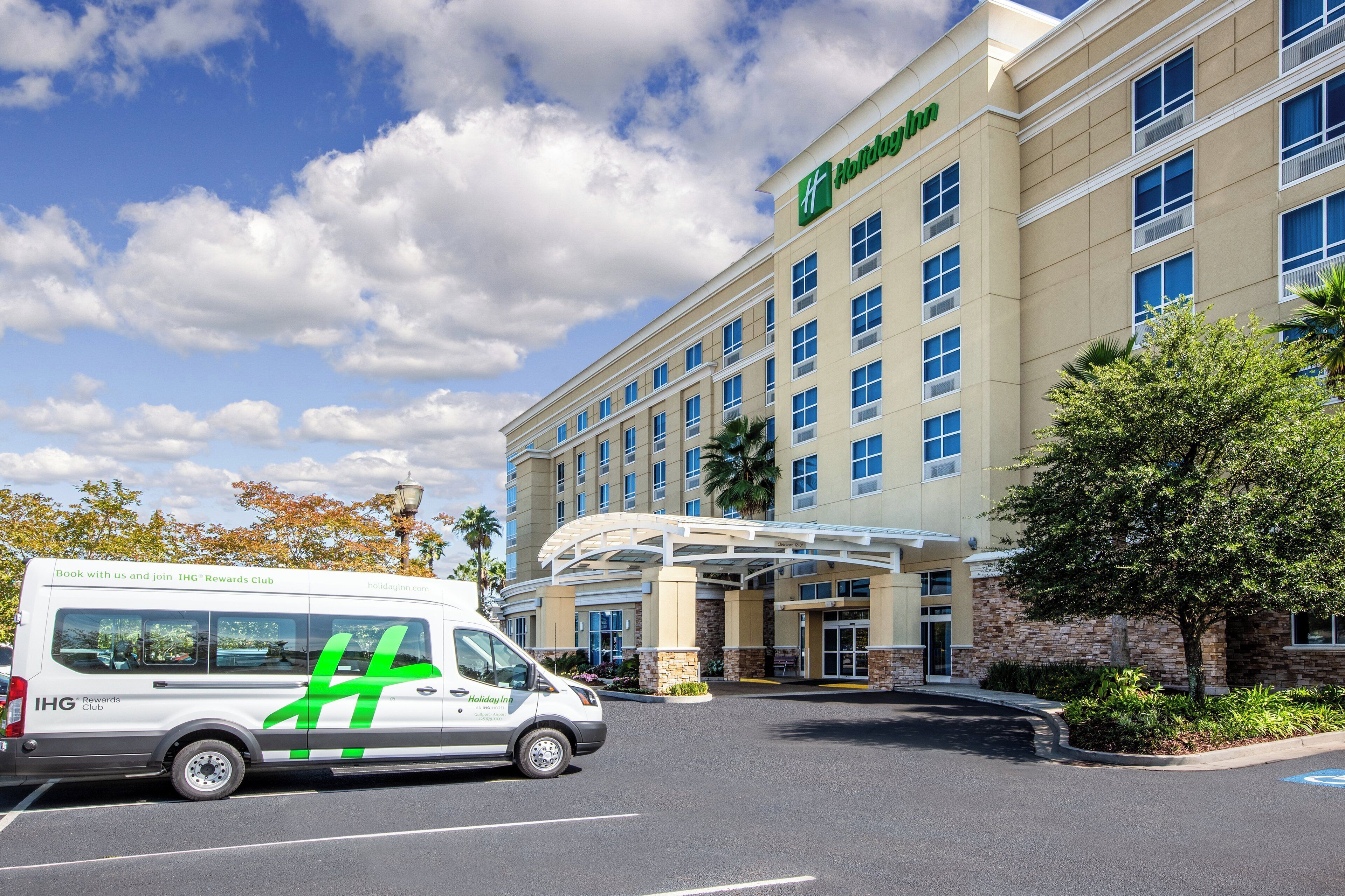 Um hotel Holiday Inn Express com estacionamento e uma van estacionada na frente.