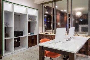 Een moderne kantoorruimte met een wit bureau, twee computerschermen, een printer en een boekenkast met decoratieve objecten.