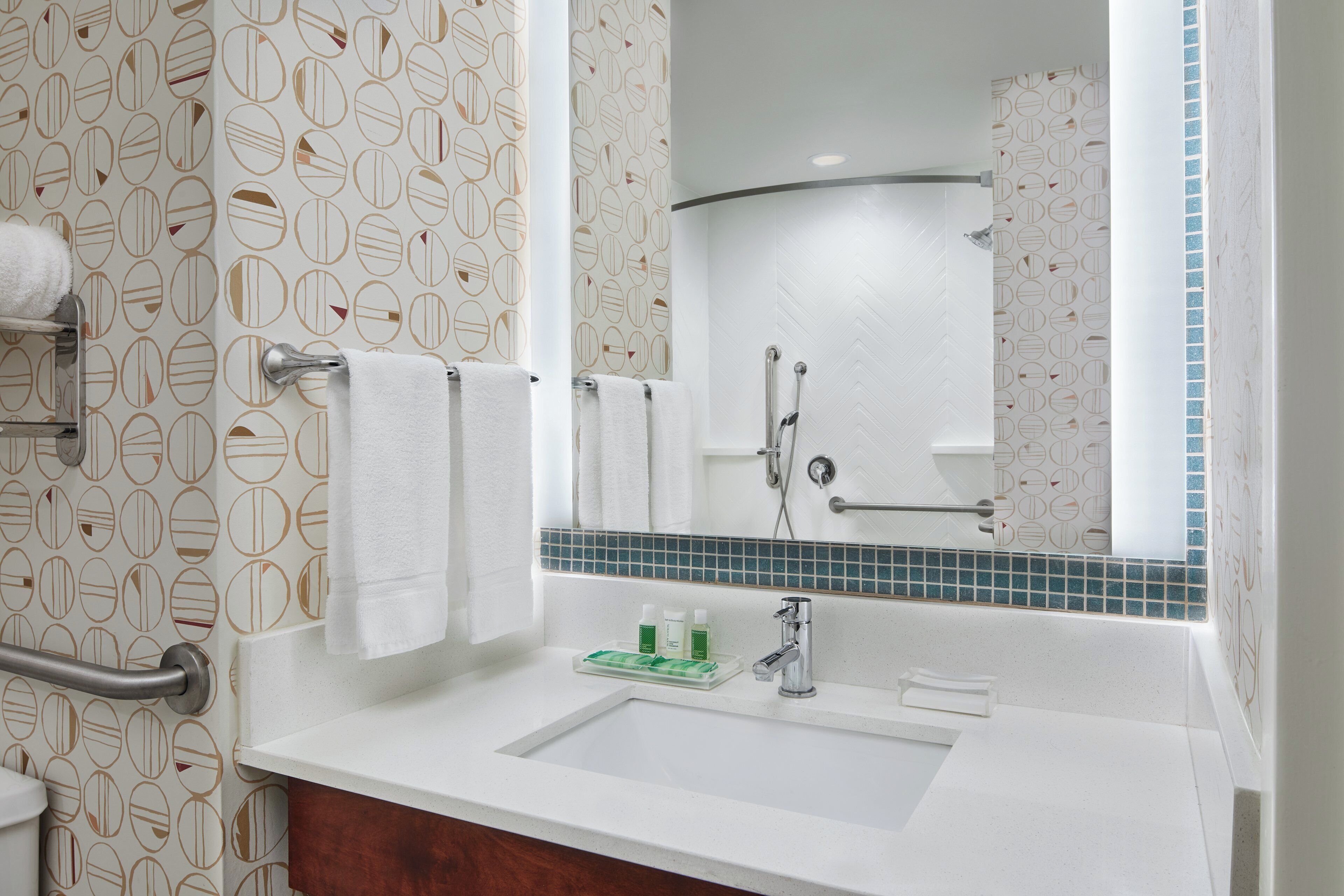 A bathroom with a white sink, a mirror, and a towel rack. There are toiletries on the sink.