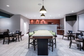 A modern dining area with a central table, chairs, and a pendant light. - Holiday Inn Gulfport Airport by IHG (Gulfport)