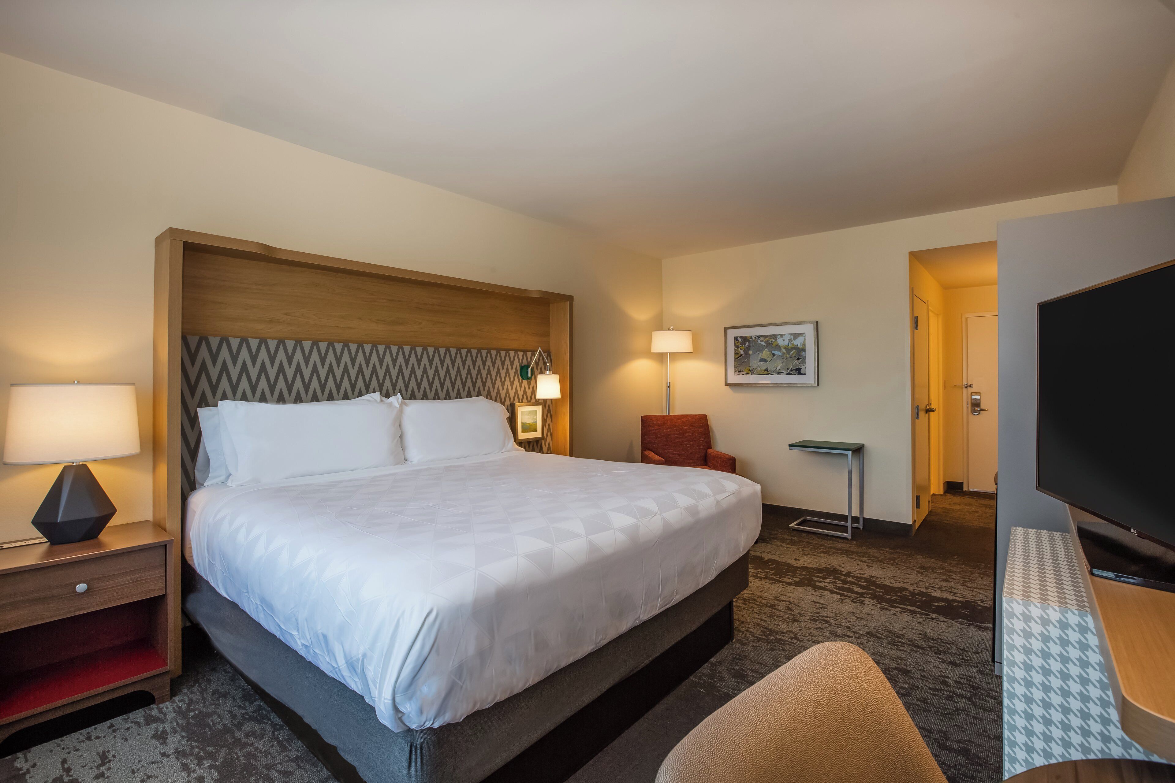 Ein Hotelzimmer mit Bett, Nachttischen, Schreibtisch, Stuhl und Fernseher.
