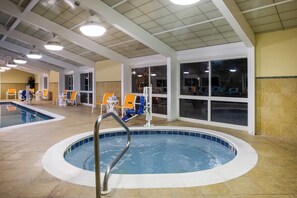 An indoor swimming pool with a metal ladder, surrounded by lounge chairs and tables. - Holiday Inn Gulfport Airport by IHG (Gulfport)
