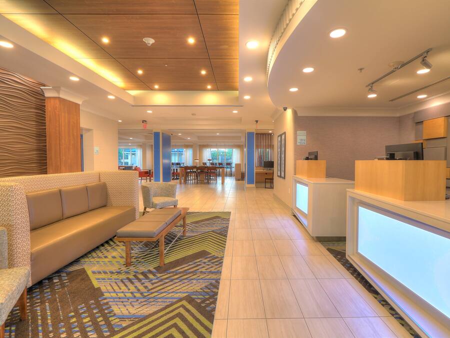 A hotel lobby with a reception desk, seating area, and a view of the dining area.