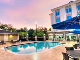 Una piscina al aire libre, sombrillas, sillones reclinables de piscina