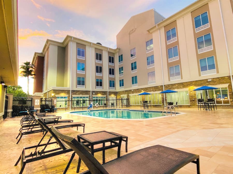 Une cour d’hôtel avec une piscine, des chaises longues et des espaces de détente en plein air.