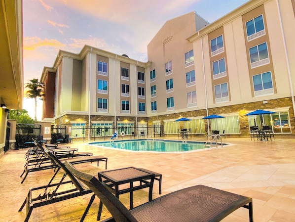 A hotel courtyard with a swimming pool, lounge chairs, and outdoor seating. - Holiday Inn Express Hotel & Suites Mobile/Saraland by IHG (Saraland)