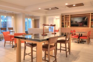 Un comedor moderno con una mesa de vidrio, sillas de madera y un televisor en la pared.