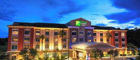 Un hotel Holiday Inn Express & Suites con un amplio estacionamiento y entrada cubierta.