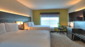 A hotel room with two beds, a desk, a chair, a TV, and a window with a view.