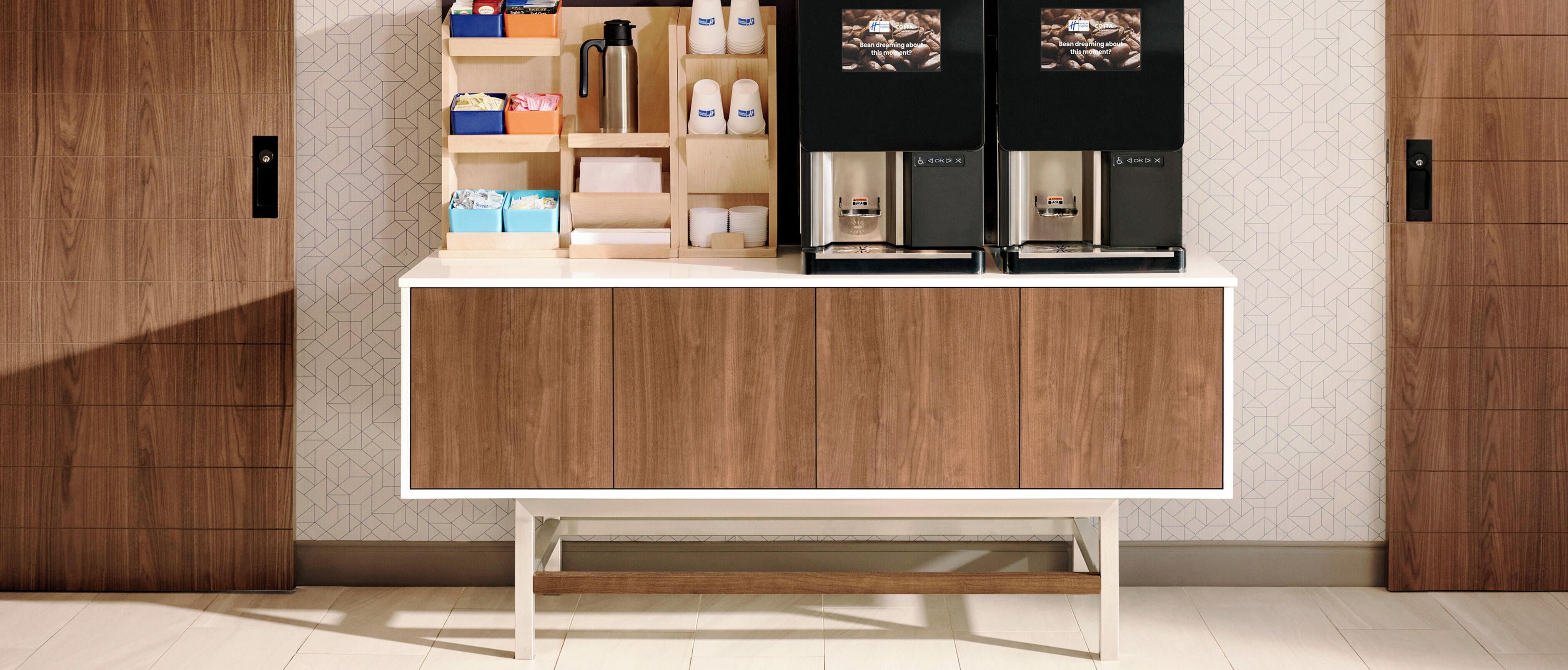 Una cocina moderna con un armario de madera, una cafetera y estantes para guardar cosas.