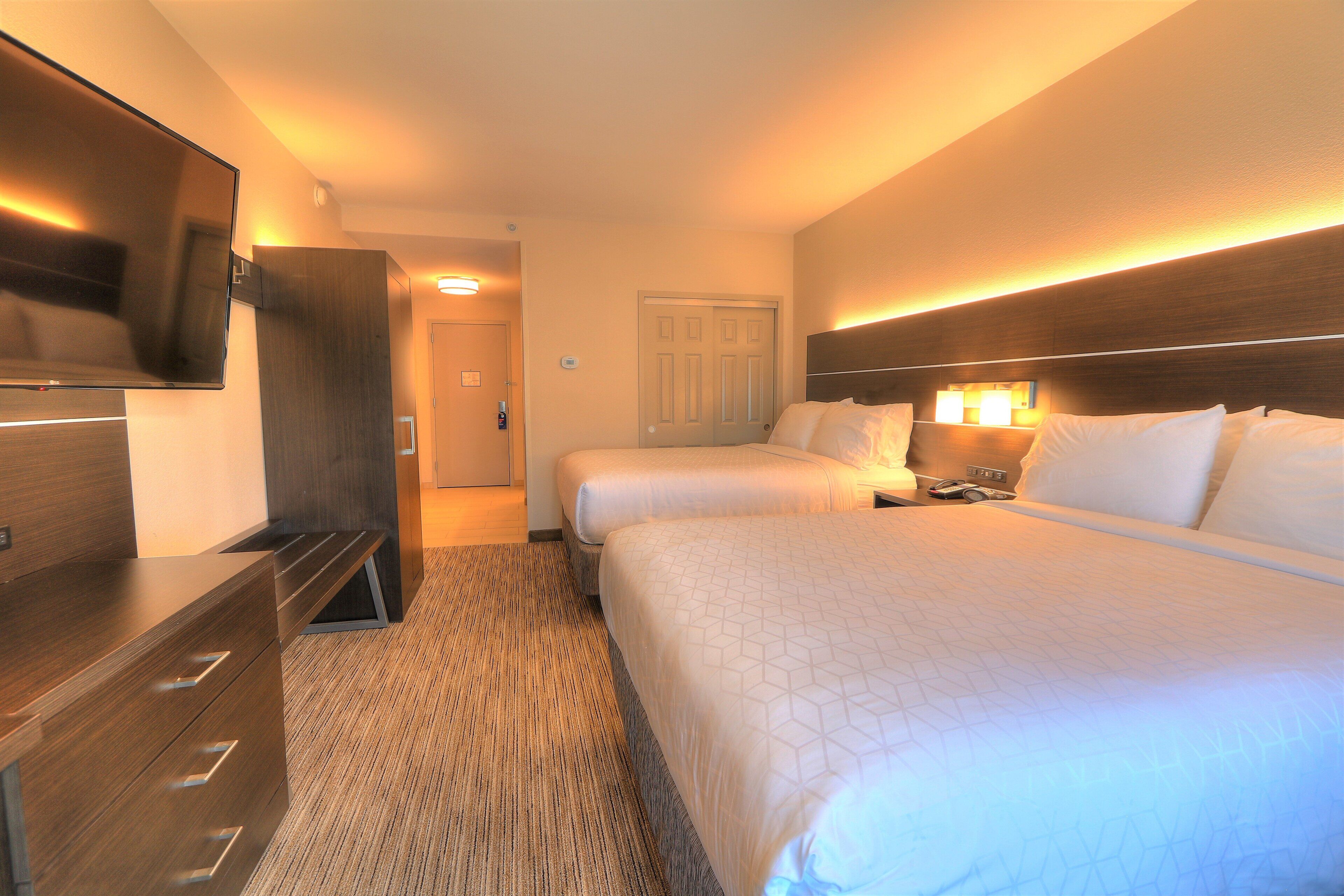 Quarto de hotel com duas camas, televisão, escrivaninha e porta.