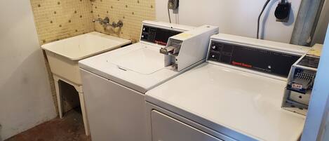 Un espace buanderie équipé de deux machines à laver et d’un évier, avec un mur recouvert de carreaux et un panneau indiquant les instructions de lavage.