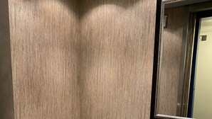 A narrow hallway with wooden walls, a tiled floor, and a mirror on the right. - Royal Pacific Motor Inn (San Francisco)
