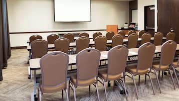 A conference room with rows of chairs, a projector screen, and a coffee station.