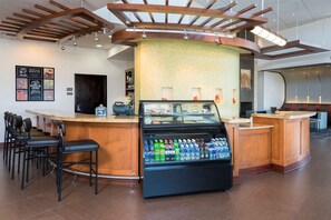 A bar area with a counter, seating, and a refrigerated display case with beverages. - Hyatt Place Lexington (Lexington)