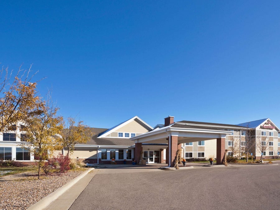 A hotel with a covered entrance, multiple windows, and a parking lot.