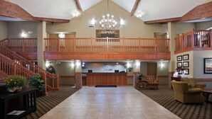Eine geräumige Lobby mit hoher Decke, einer Kristallleuchter, einem Empfangstisch und einer Treppe, die in ein Obergeschoss führt.