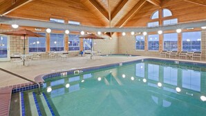 Ein Innenpool mit Holzbalken, gefliesten Wänden und Sitzbereichen.