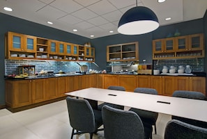 A modern kitchen with wooden cabinets, a large island, and a dining area with a table and chairs.