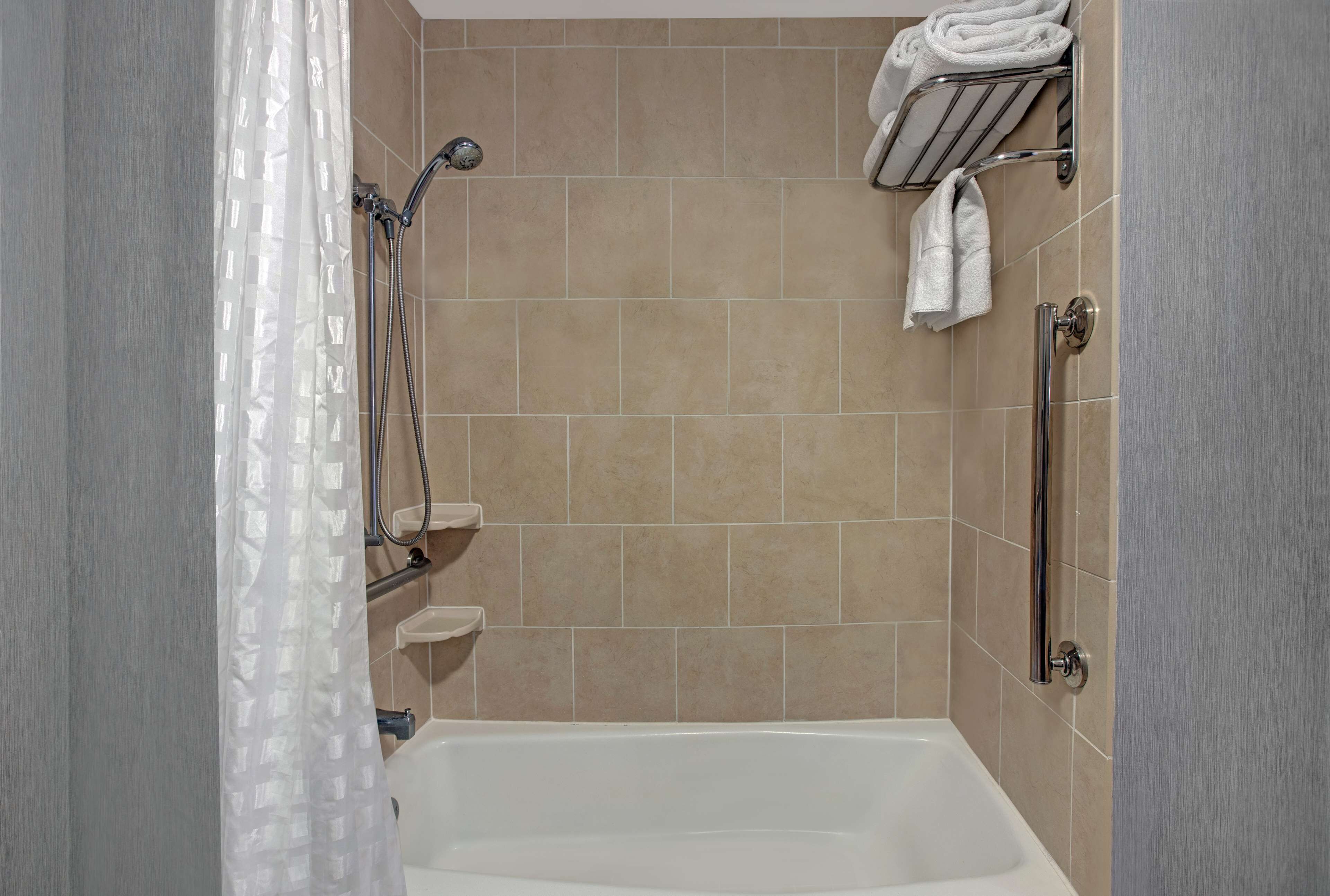 A bathroom with a bathtub, a shower, and a towel rack with towels.