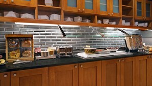 A buffet setup with wooden cabinets, a brick backsplash, and various food items displayed on the counter.