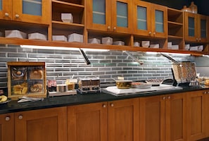A buffet setup with wooden cabinets, a brick backsplash, and various food items displayed on the counter.