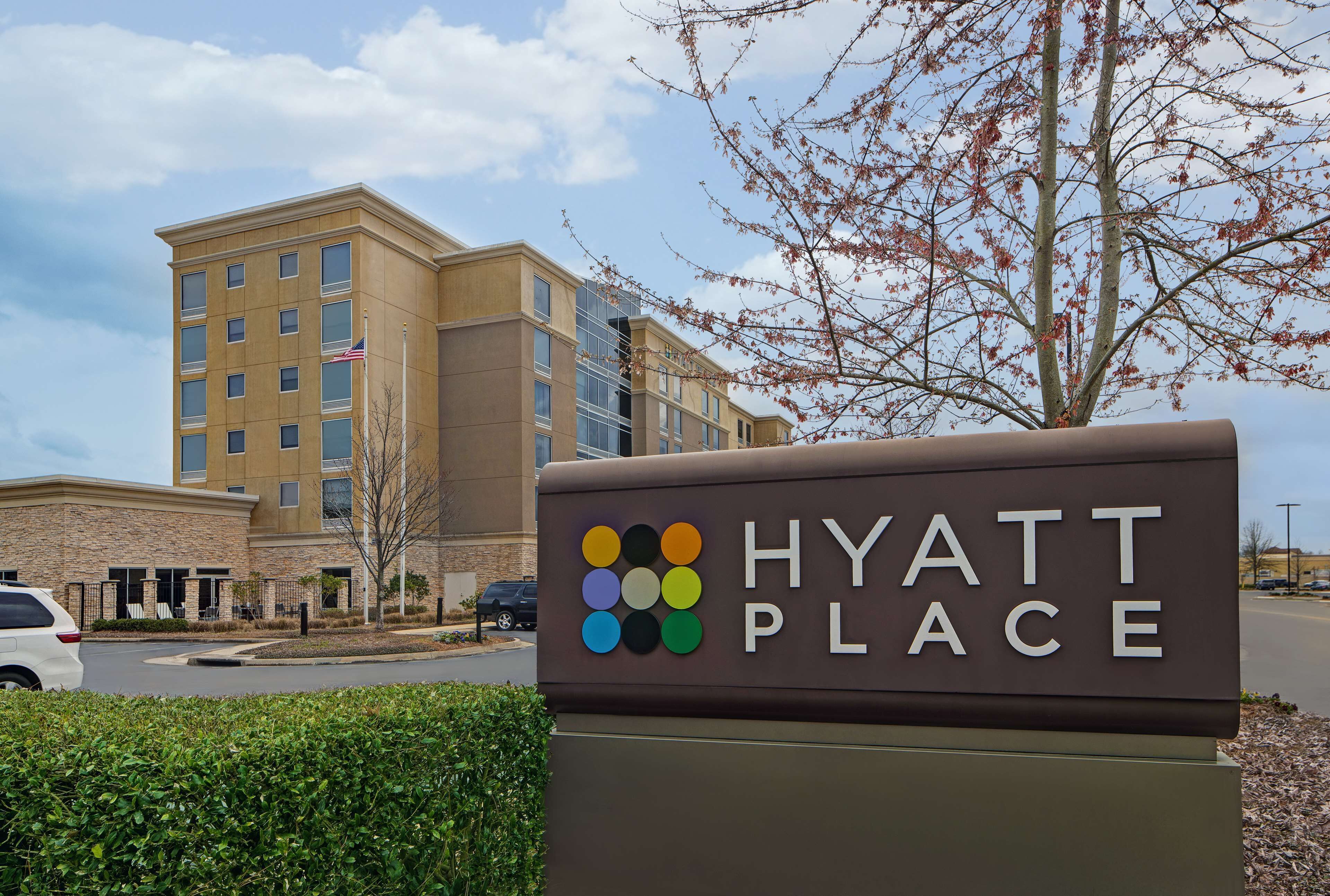 A sign for a Hyatt Place hotel with a clear view of the building in the background.