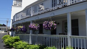 A white building with a balcony and hanging flower baskets. - Pink Blossom Family Resort (Ogunquit)