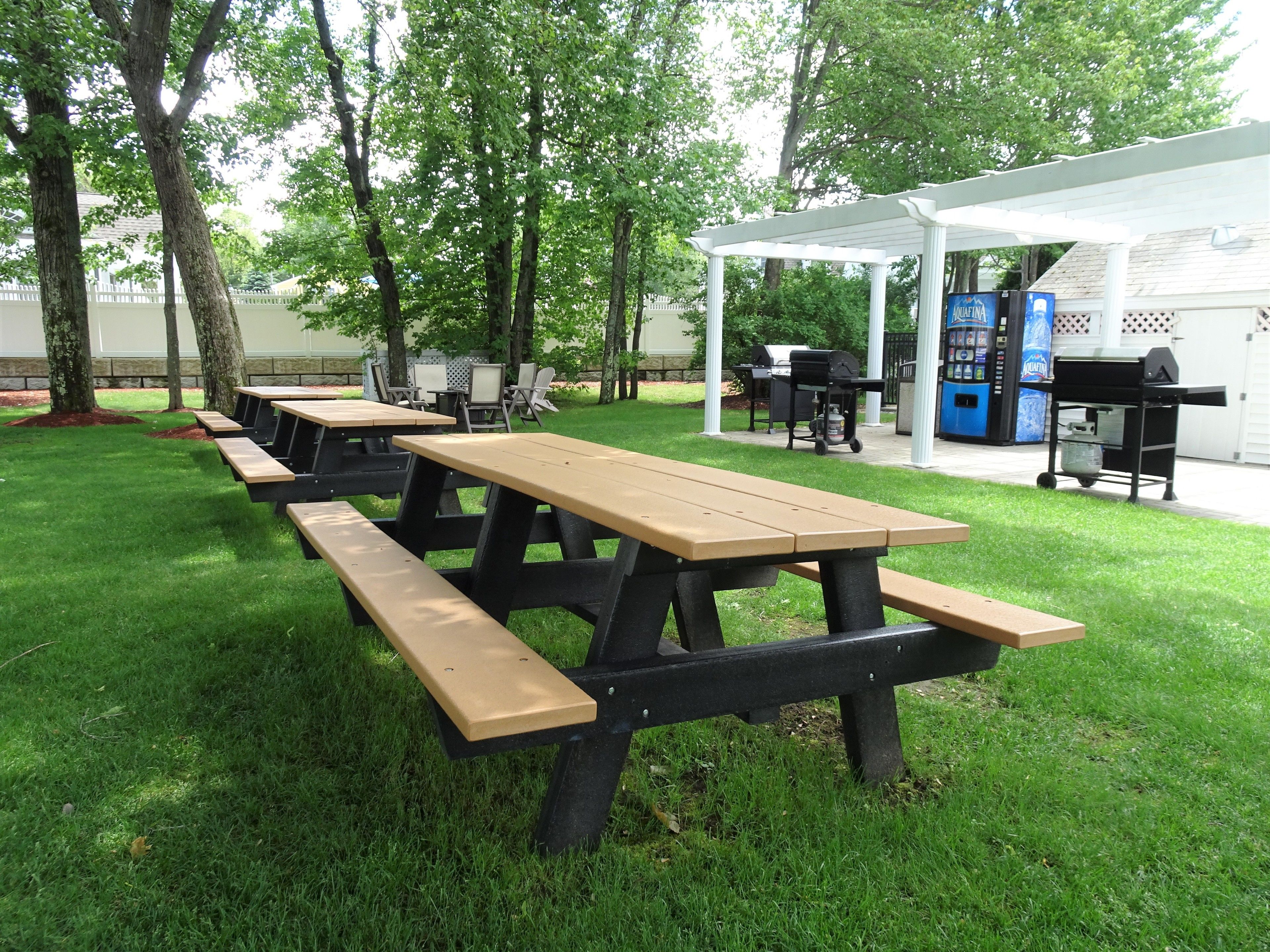 A picnic area with several wooden picnic tables and a barbecue setup.