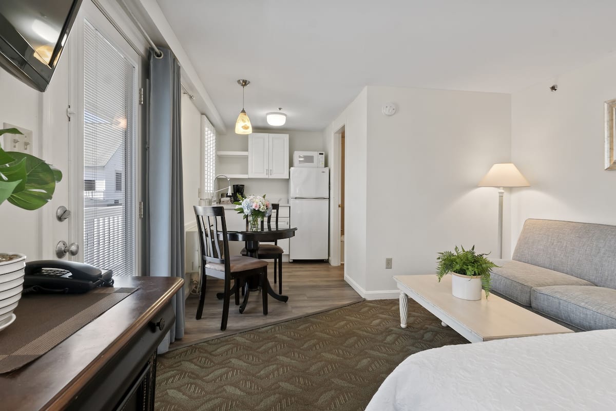 Een modern appartement met keuken, eethoek en woonkamer met een bank en lamp.