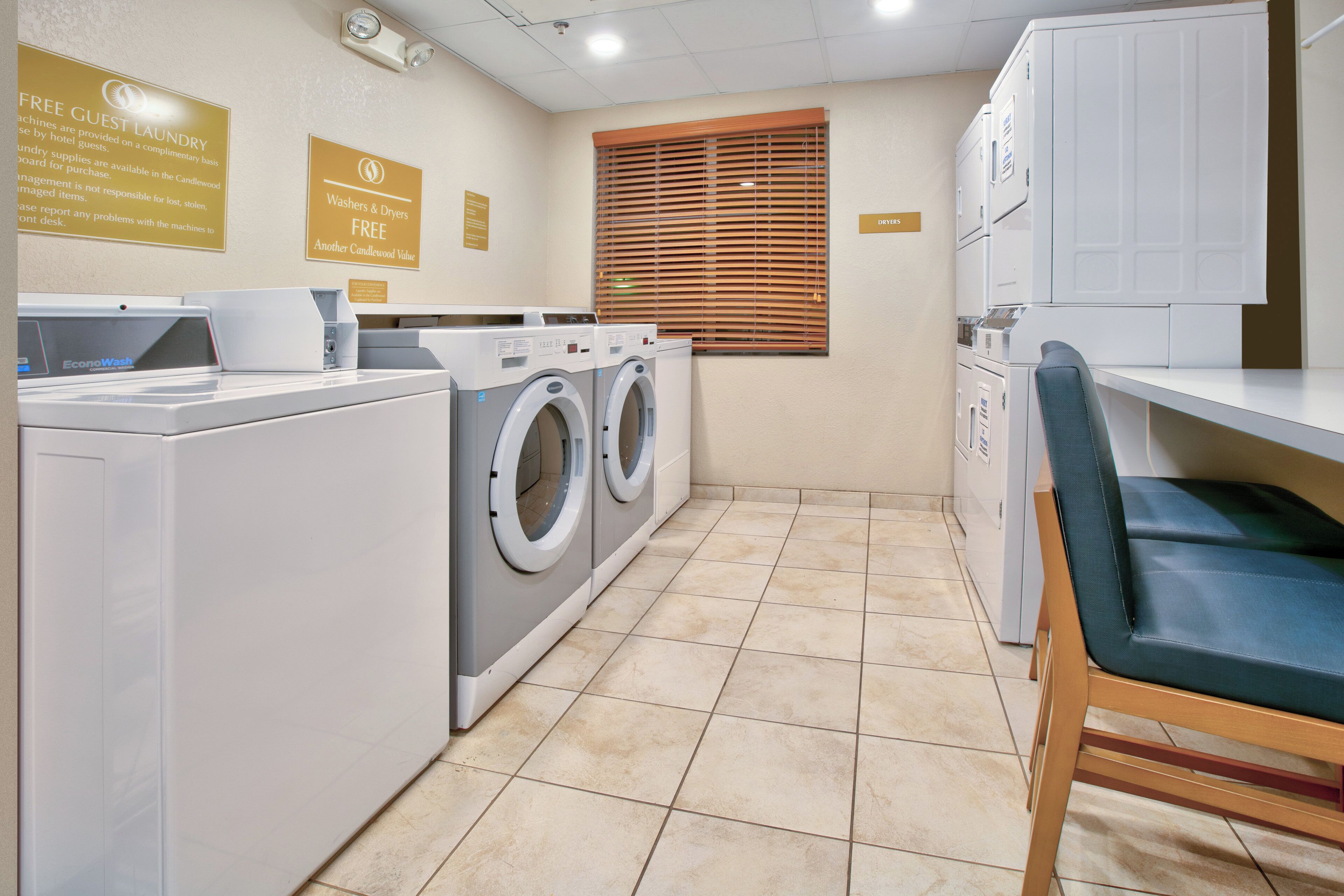 A laundry room with washers and dryers, a chair, and signs indicating free guest laundry services.