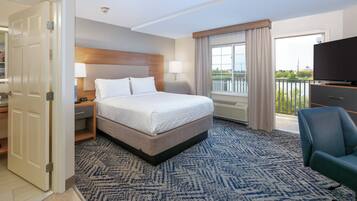 A hotel room with a bed, bedside tables, a TV, a chair, and a view of the outdoors.