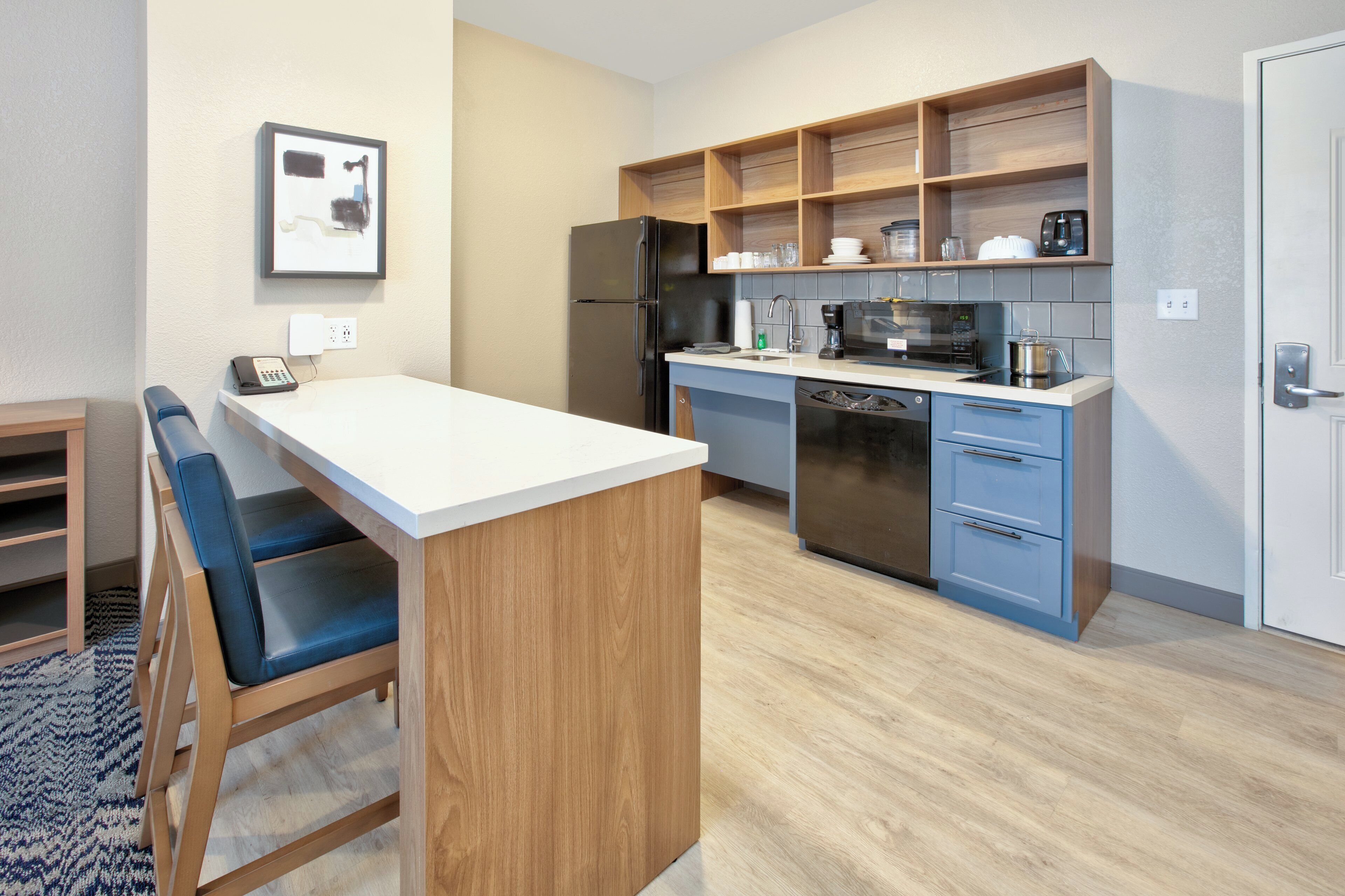 A modern kitchen with a central island, a refrigerator, a microwave, and a dishwasher.