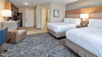 Une chambre d’hôtel avec deux lits, un bureau avec une chaise, une kitchenette et une salle de bain.