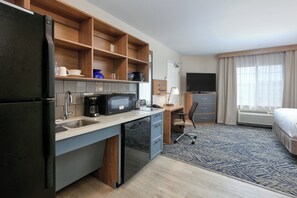 A compact hotel room with a kitchenette, a bed, a desk, and a TV. - Candlewood Suites Idaho Falls by IHG (Idaho Falls)