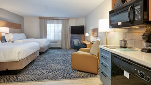 A hotel room with two beds, a desk, a microwave, and a coffee maker.