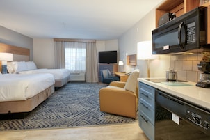 Habitación de hotel con dos camas, un escritorio, microondas y cafetera.