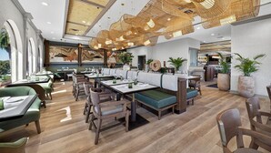 A modern restaurant with wooden flooring, green upholstered seating, and a unique ceiling design. - Mission Resort and Club (Howey-in-the-Hills)